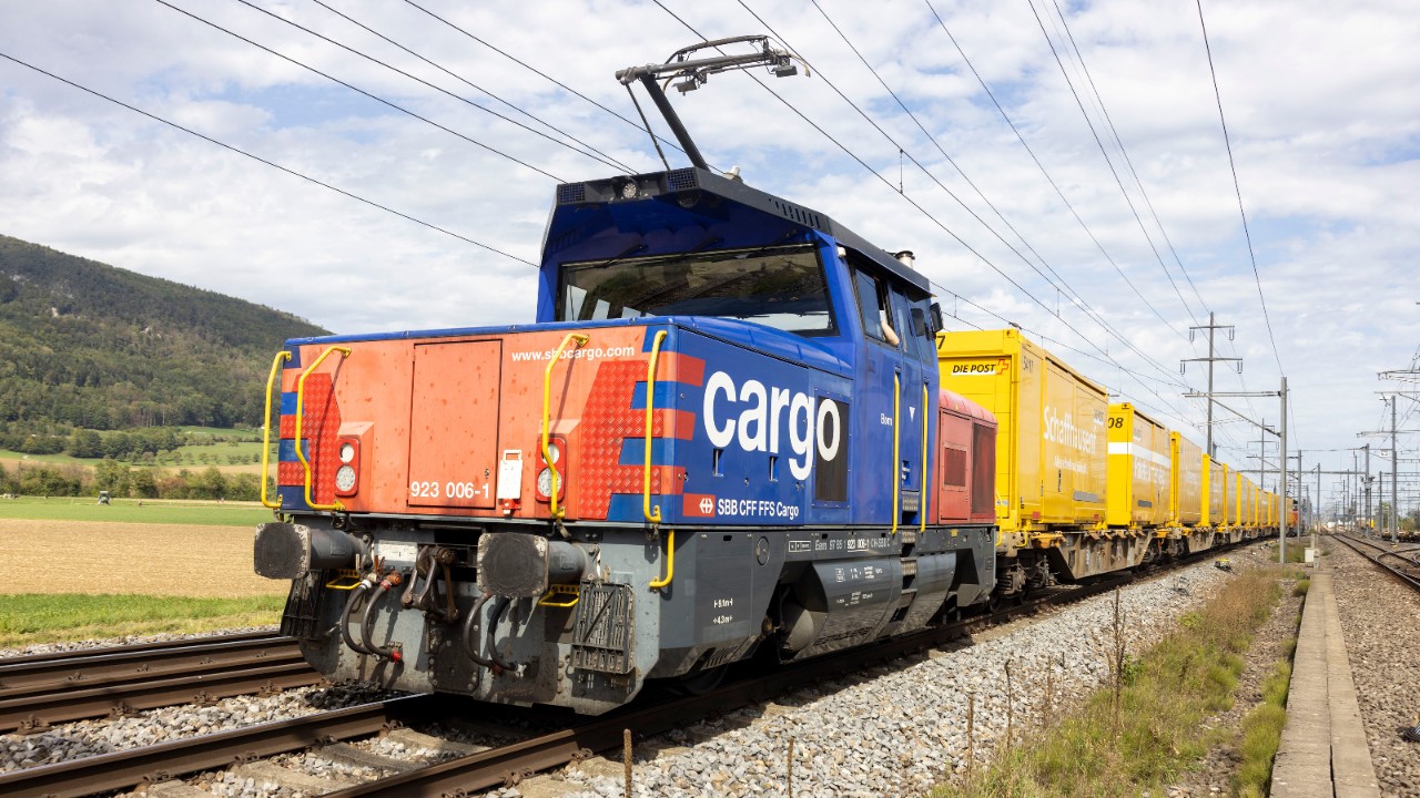 Des wagons de la Poste tractés par une locomotive ambimoteur de CFF Trafic marchandises.