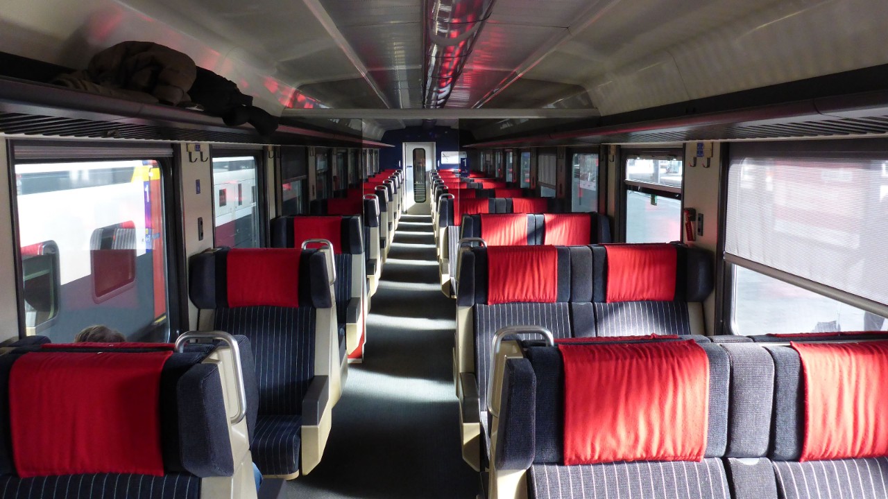 La photo représente l’intérieur d’un wagon de chemin de fer. La lumière est éteinte.