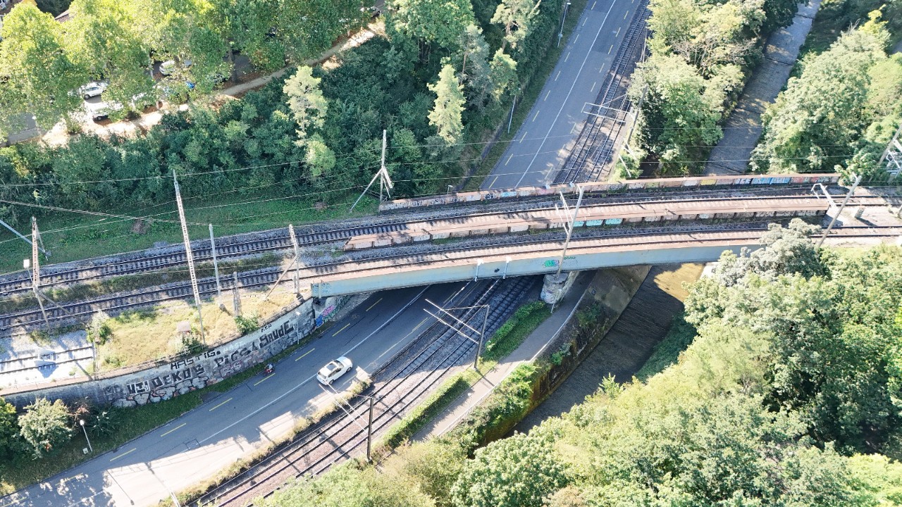 Das Foto zeigt zwei parallel verlaufende Brücken. Sie werden von einer Strasse, zwei Tramgleisen und einem Fluss unterquert.  