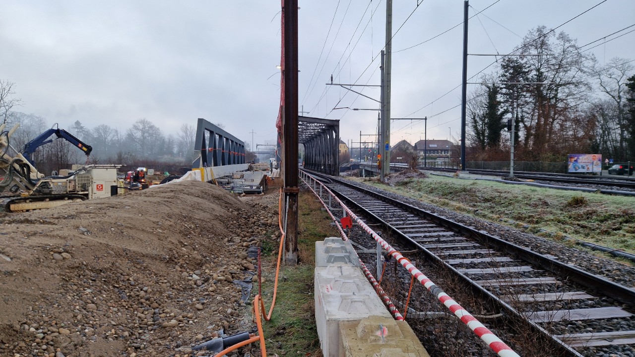 Zwei Brücken liegen nebeneinander. Links sieht man das Stahlfachwerk der neuen Brücke zu der noch keine Gleise führen. Rechts liegt das Stahlfachwerk der alten Bahnbrücke, welche noch in Betrieb ist. 