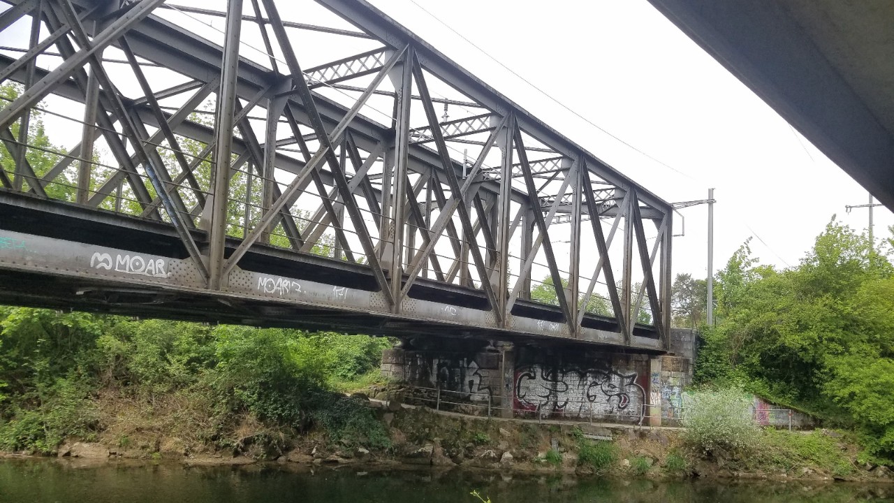 Die alten Birsbrücken von Münchenstein in Richtung Basel gesehen. Im Vordergrund links verläuft die untere Brücke, dahinter liegt die obere Brücke. Rechts oben im Bild verläuft die Trambrücke.