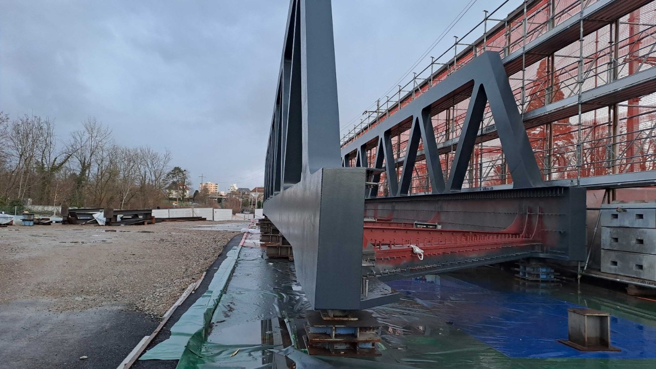 Das Foto zeigt ein fertiggestelltes Stahlfachwerk ohne die zuvor vorhandene Einhausung. Materialien und eine blaue Abdeckung sind im Vordergrund sichtbar, während der Himmel dahinter bewölkt ist.