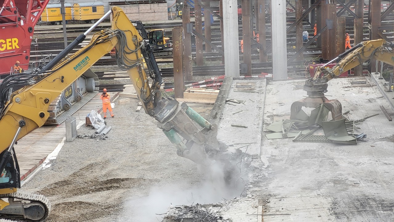 Zwei Bagger zerkleinern ein ausgehobenes Brückenelement. 