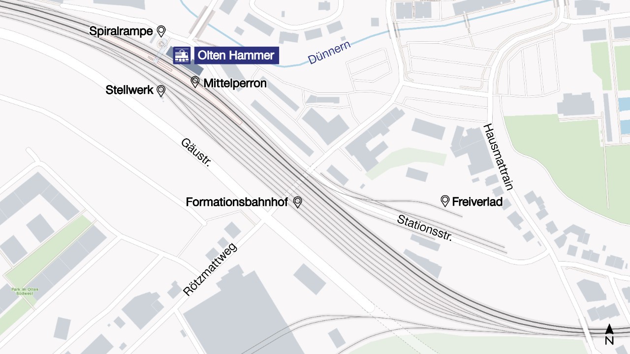 Die Grafik zeigt eine schematische Übersicht des Bahnhofs Olten Hammer mit Gleisanlagen, dem Mittelperron und angrenzenden Bereichen. Eingezeichnet und beschriftet sind unter anderem Spirrampe, Stellwerk, Formationsbahnhof, Freiverlad sowie umliegende Strassen und der Fluss Dünnern. Die Darstellung ordnet die bestehenden Bahnhofselemente räumlich im Quartier ein.