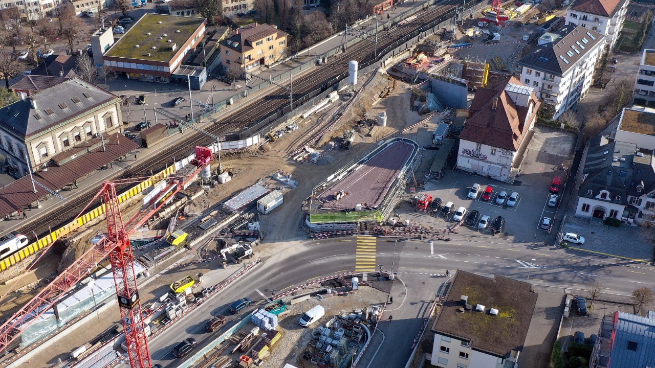 Das Foto vom Januar 2022 zeigt die Situation vom selben Blickwinkel aus. Links davon – unter den Plastikplanen – liegt die Rampe, die künftig von der Unterführung zum nenen Gemeinschaftsperron von SBB und Waldenburgerbahn führt. Hinter dem Unterführungszugang laufen die Arbeiten für die Verlängerung der Wegunterführung Orisbach. 
